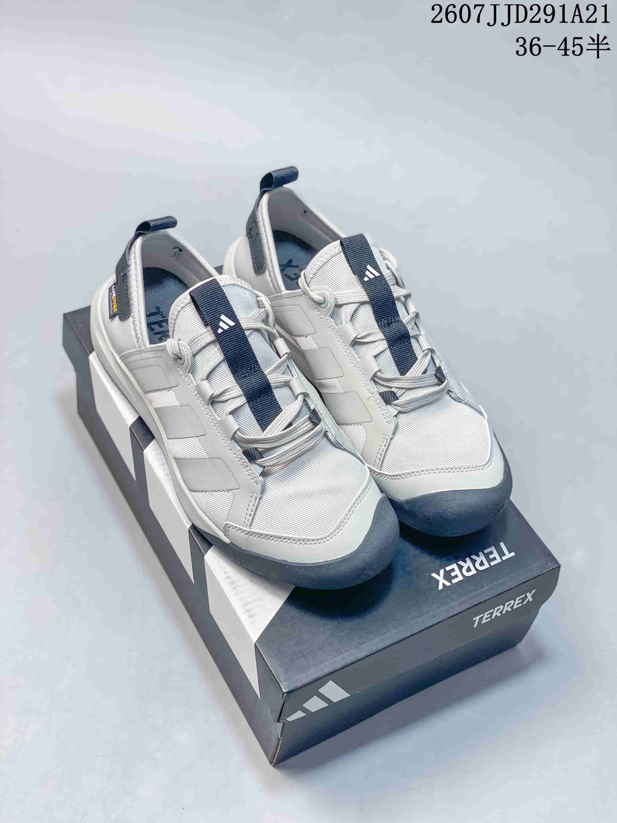 Pair of white and navy adidas Terrex hiking shoes displayed on a branded shoebox.
