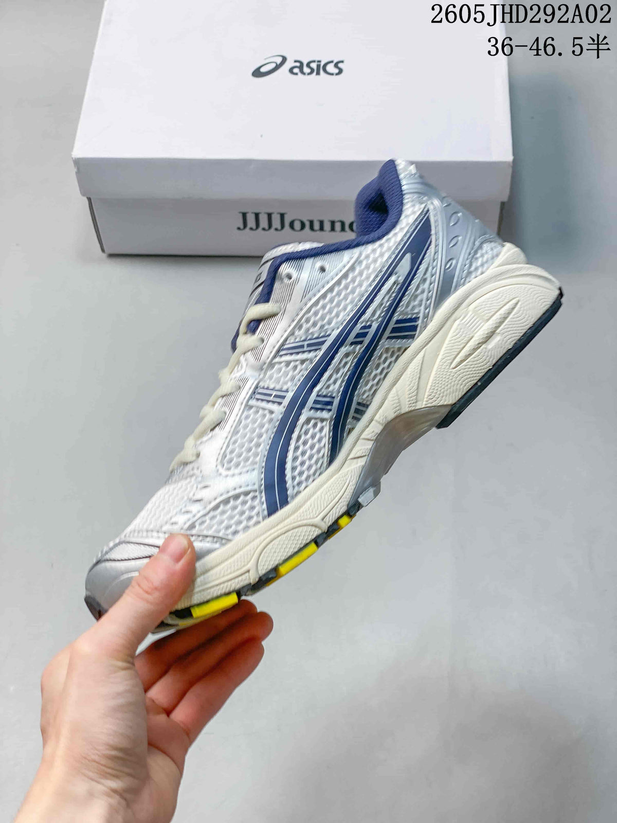 Side view of the silver-toned sneaker with dark blue accents and a layered sole