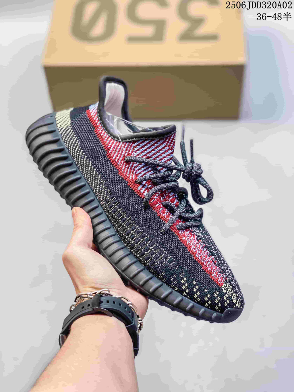 Black, gray and red Adidas Yeezy-style sneaker with a textured upper and ridged sole.