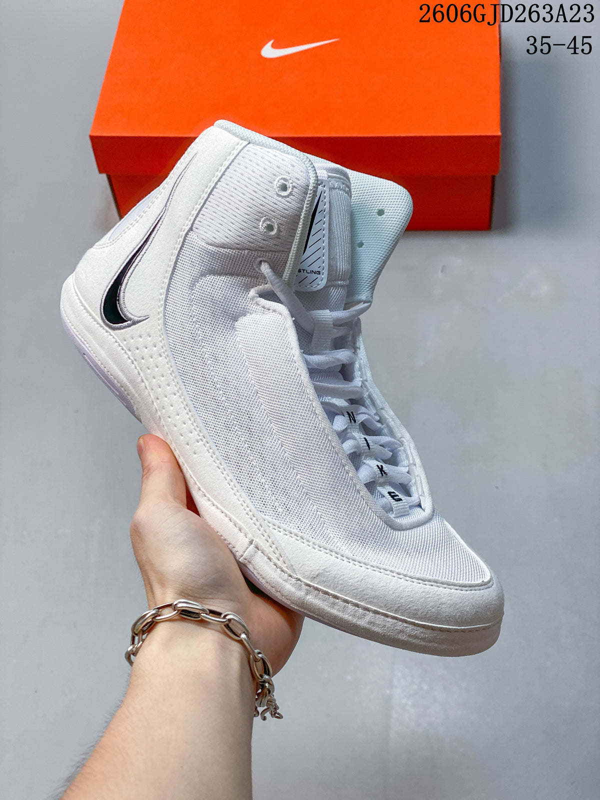 Side view of a white Nike Inflict 4 wrestling shoe with mesh-like panels and a dark Swoosh.