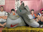 Pair of grey Nike basketball shoes showing the red and teal Swoosh details and strap closures.