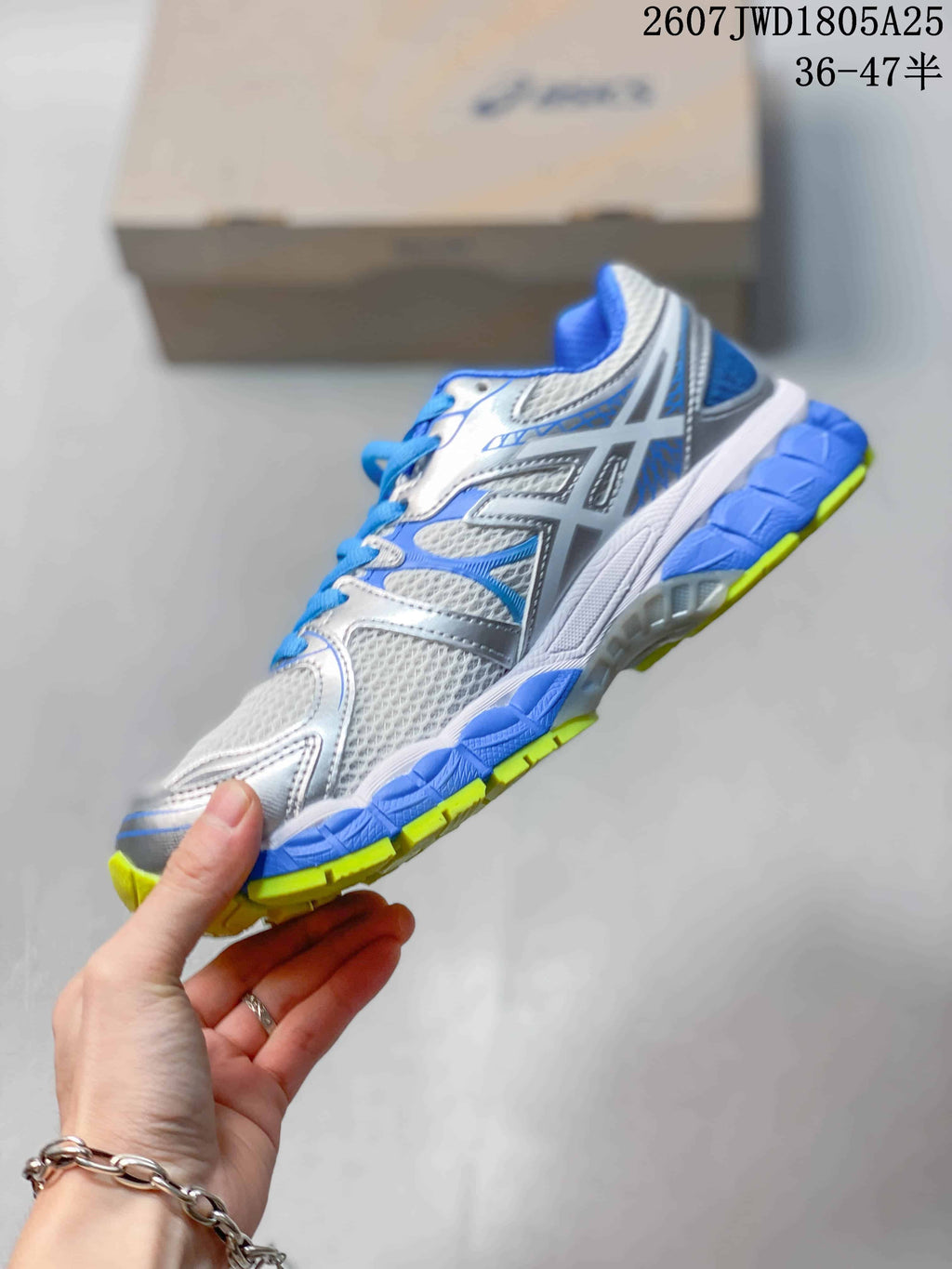 Side profile of the ASICS sneaker showing the layered upper, side branding, and blue and neon yellow sole.