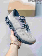 Close-up side view of a gray On Cloud X 4 sneaker with a dark segmented sole.