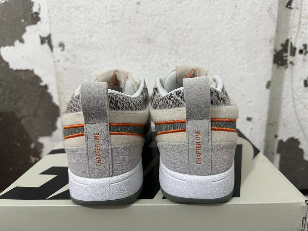 Rear view of gray, off-white, and orange Nike Book 1 sneakers showing patterned collars and heel details.
