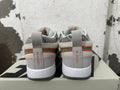 Rear view of gray, off-white, and orange Nike Book 1 sneakers showing patterned collars and heel details.