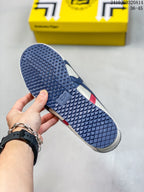 Underside view showing the dark blue patterned rubber outsole and the side stripes of the sneaker.