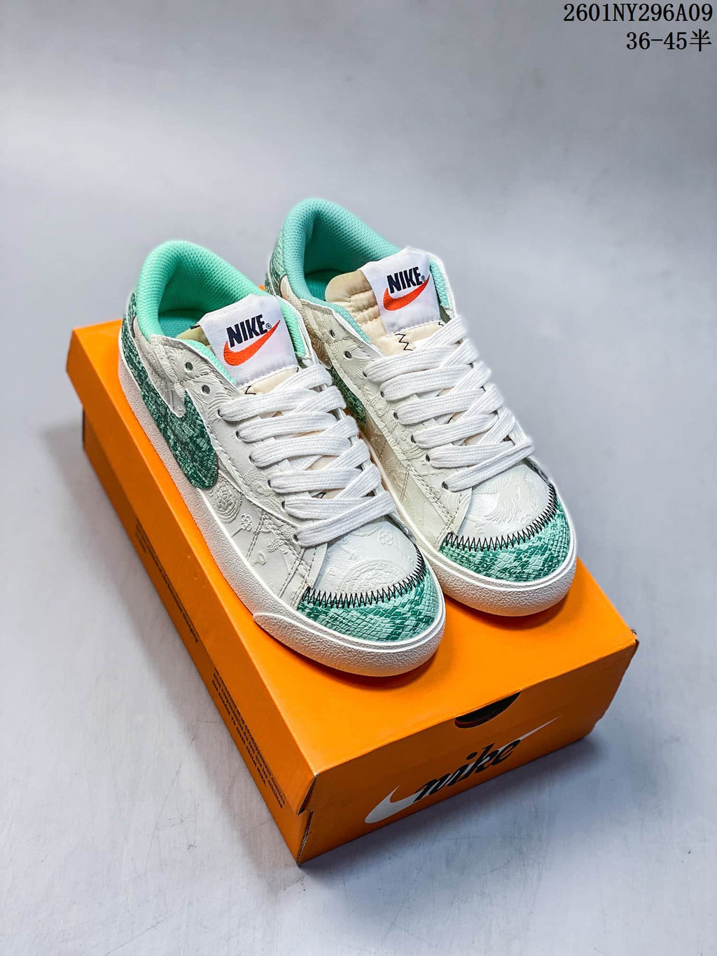Pair of white and green Nike Blazer Low ’77 Jumbo sneakers displayed on an orange shoebox.