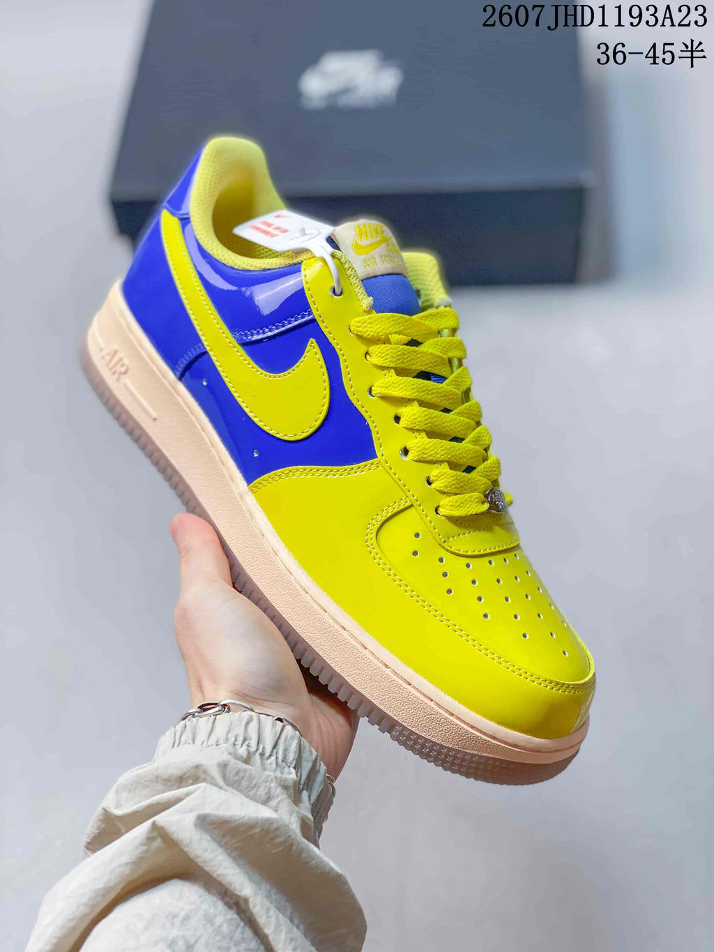 Angled side view highlighting the glossy blue panels, yellow Swoosh, yellow toe area, and light-colored sole.