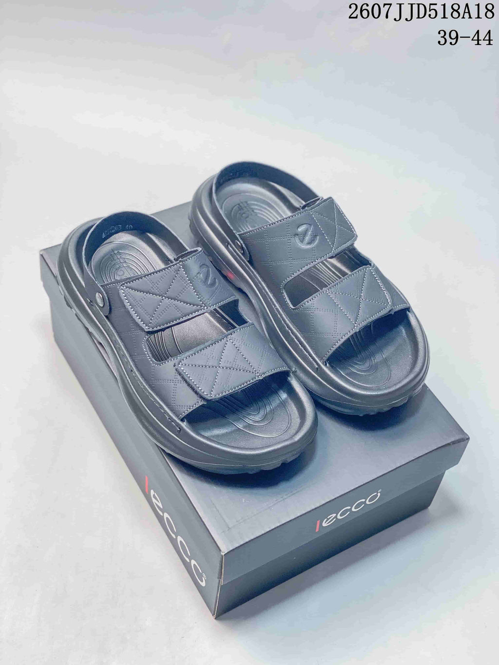 Pair of black ECCO sandals displayed on a branded shoe box, showing two adjustable straps and heel straps.
