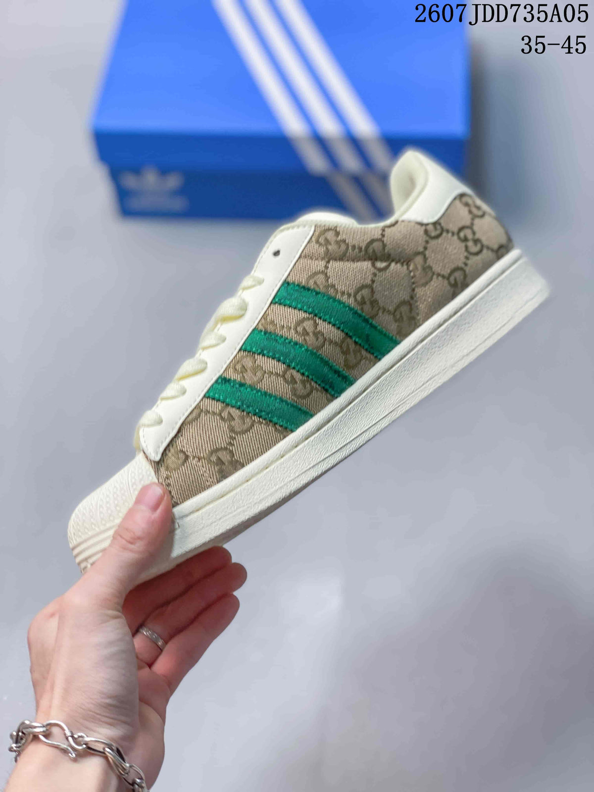 Side profile showing the beige patterned upper, green three-stripe detail, shell toe, and off-white sole.