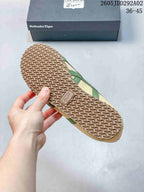 Underside view of an Onitsuka Tiger sneaker showing the repeating textured outsole pattern and branded outsole insert; a branded shoe box is in the background.