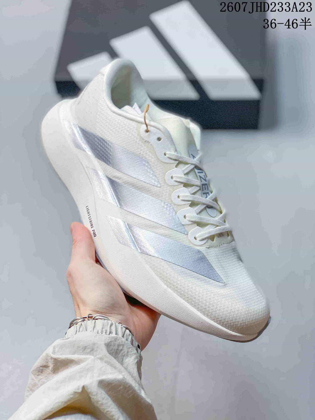Angled side view of the white Adidas sneaker showing the layered side stripes, lace system, and thick sole.