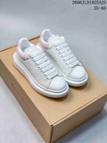 White textured low-top sneakers with pink heel panels and thick white platform soles, shown on a box.