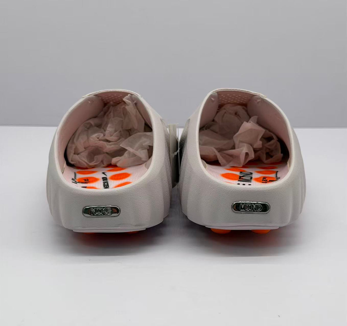 Rear view of the pair with heel branding, open-back construction, and pink-and-orange footbed details.
