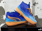 Pair of blue Puma Melo basketball shoes shown from the side, highlighting the light blue and yellow-orange color blocking.