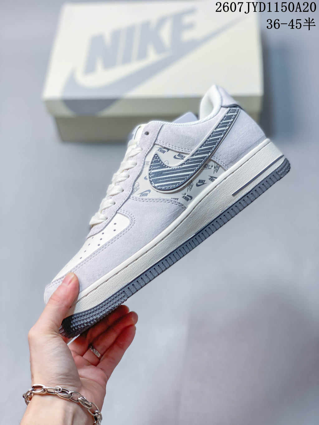 Side profile of the white and gray low-top sneaker showing layered panels, patterned Swoosh, and printed side detailing.