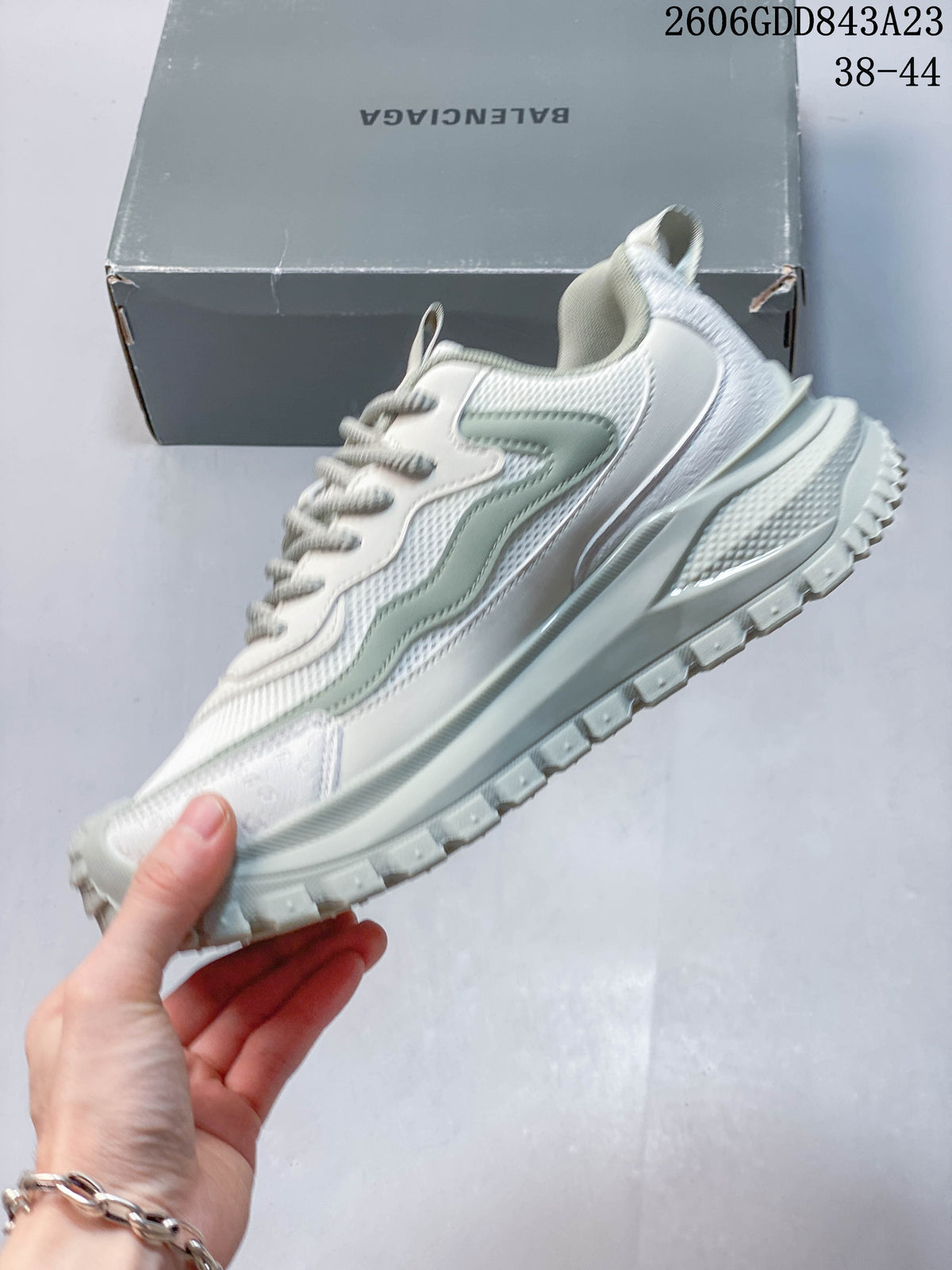 Side view of the white and pale sage sneaker with layered panels and a thick treaded sole.