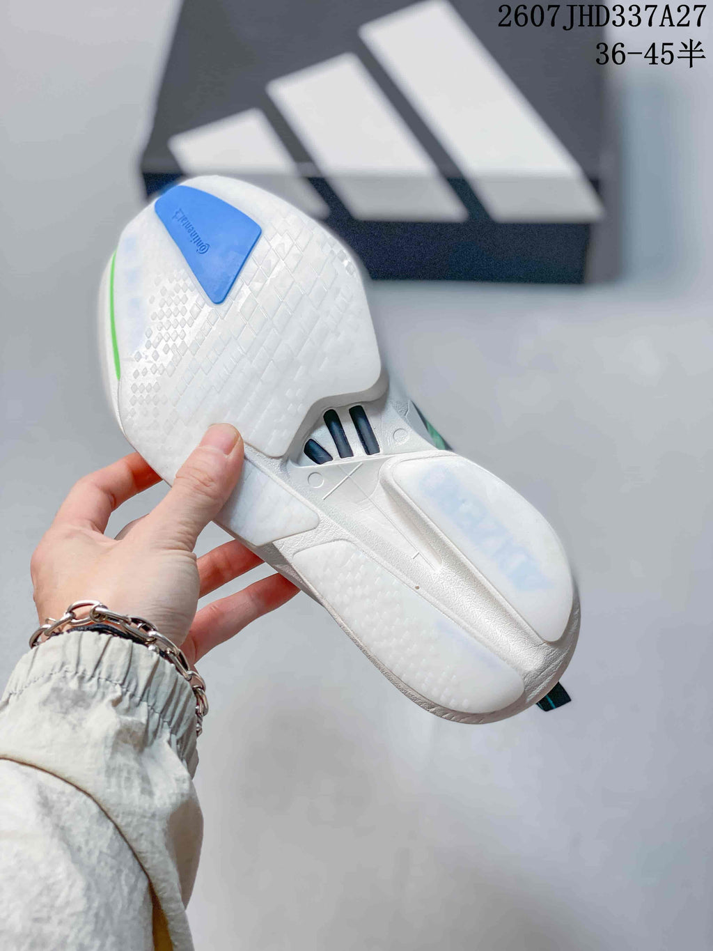 Underside view of the white sneaker outsole showing textured tread, blue heel detail, and translucent outsole sections.