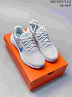 Pair of light gray and white Nike Vomero 18 running shoes with blue accents displayed on an orange shoebox; text shows style code 2607JHY971A21 and size range 36–40.5.