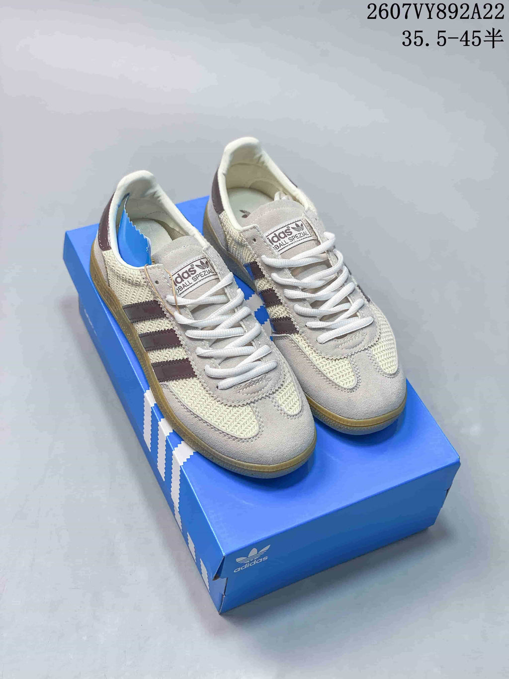 Pair of white low-top sneakers with textured panels, dark burgundy side stripes, gum soles, and Spezial tongue labels.