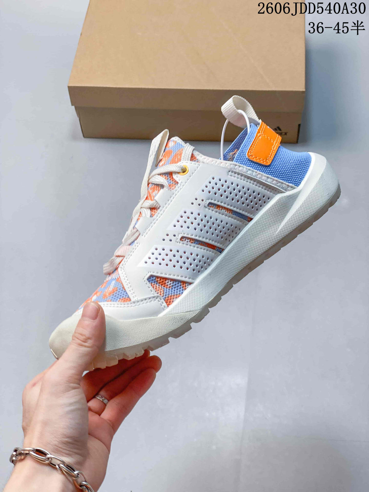 Side view showing perforated white panels, patterned upper, and blue and orange heel accents