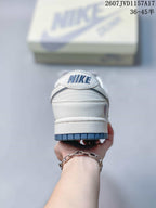 Rear view of the white low-top sneaker with a blue outsole edge and Nike branding on the heel tab.