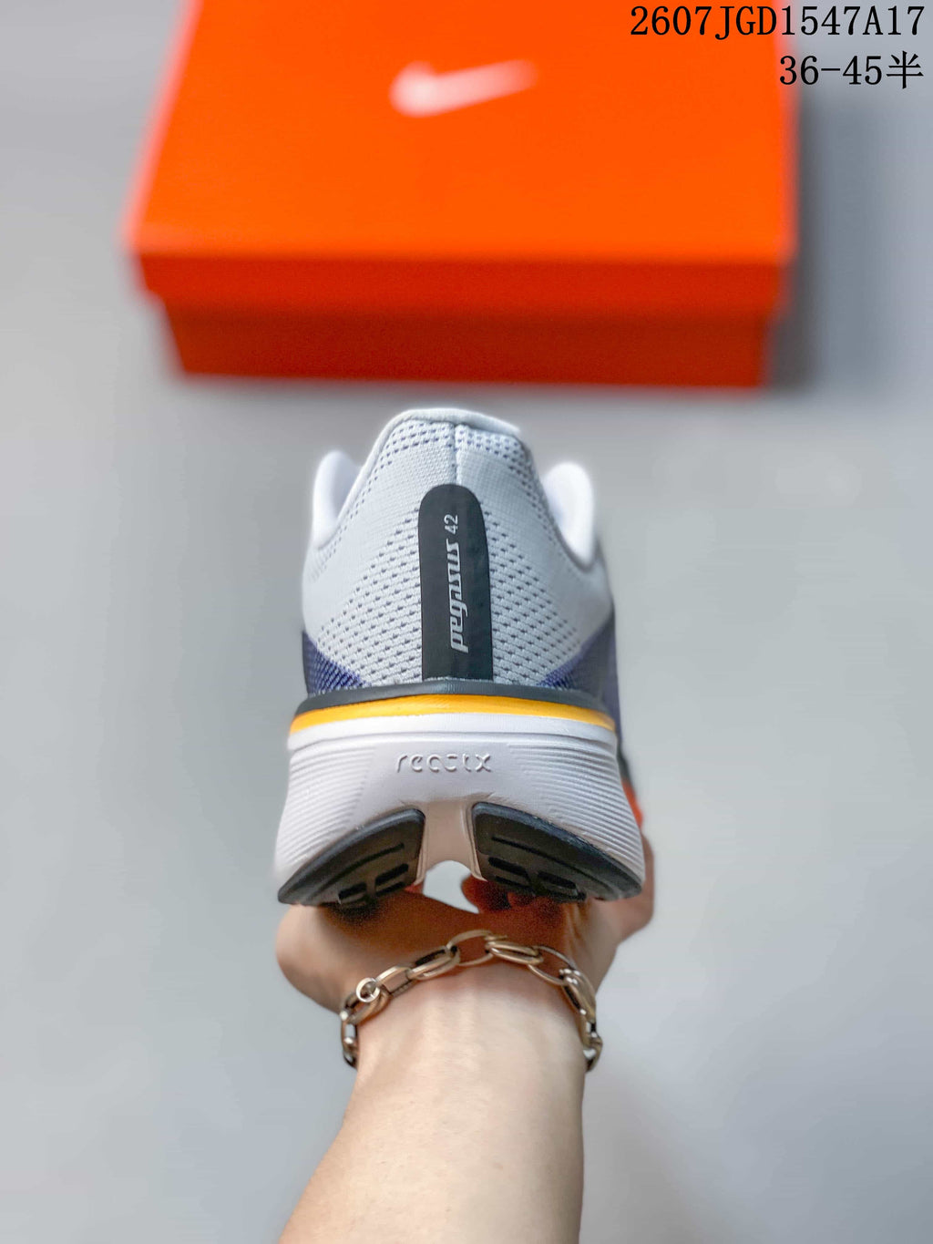 Rear view of a Nike Pegasus 42 shoe showing the heel branding, white upper and orange midsole accent.