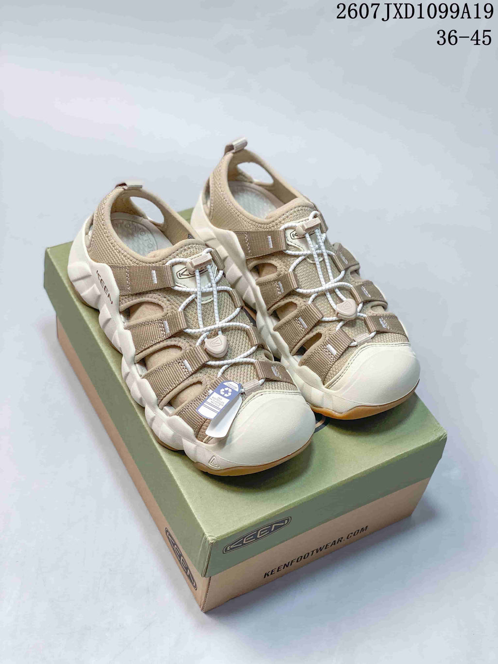 Pair of beige Keen Astoria West closed-toe outdoor sandals displayed on a branded box; overlay shows style code 2607 JXD1099A19 and size range 36–45.