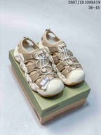 Pair of beige Keen Astoria West closed-toe outdoor sandals displayed on a branded box; overlay shows style code 2607 JXD1099A19 and size range 36–45.