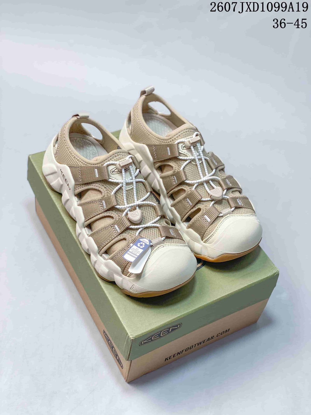 Pair of beige Keen Astoria West closed-toe outdoor sandals displayed on a branded box; overlay shows style code 2607 JXD1099A19 and size range 36–45.