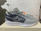 Side view of a grey Nike basketball shoe with dark mesh panel, white Swoosh, and Zoom midsole marking.