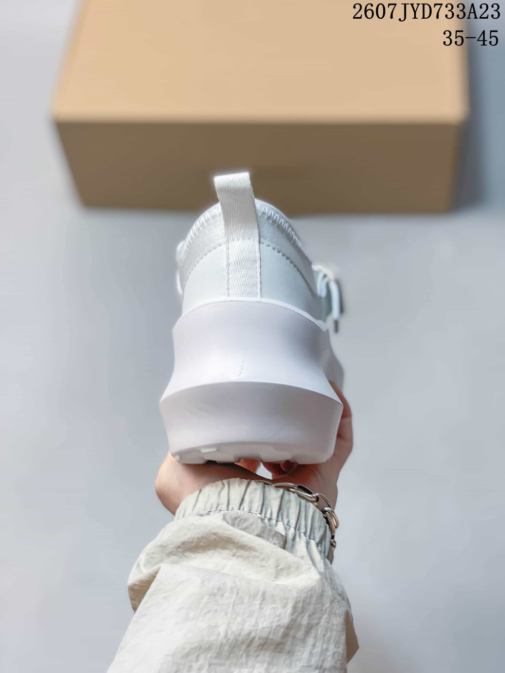 Rear view of the white sneaker showing the heel pull tab, padded collar, and raised platform sole.