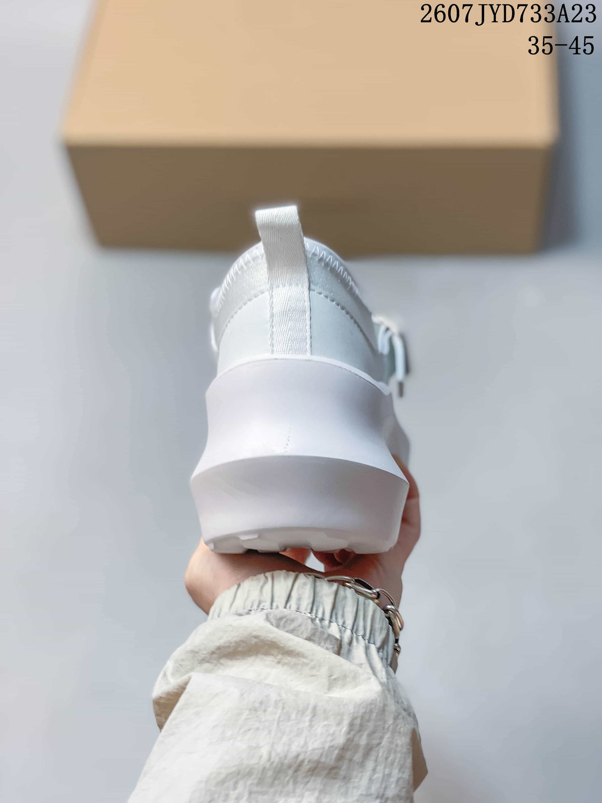 Rear view of the white sneaker showing the heel pull tab, padded collar, and raised platform sole.