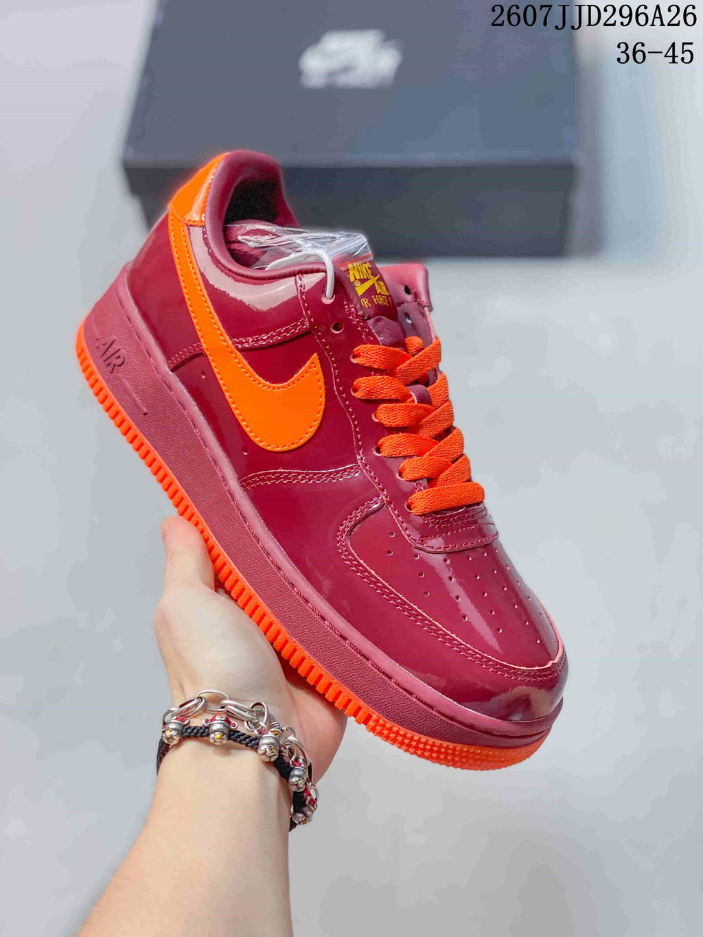 Angled side view of the burgundy and orange low-top sneaker showing the orange Swoosh, laces, and outsole.