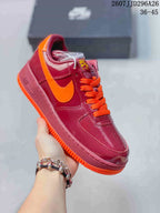 Angled side view of the burgundy and orange low-top sneaker showing the orange Swoosh, laces, and outsole.