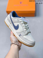 White low-top sneaker with a dark blue swoosh-style overlay, blue collar trim, and gum-colored outsole.
