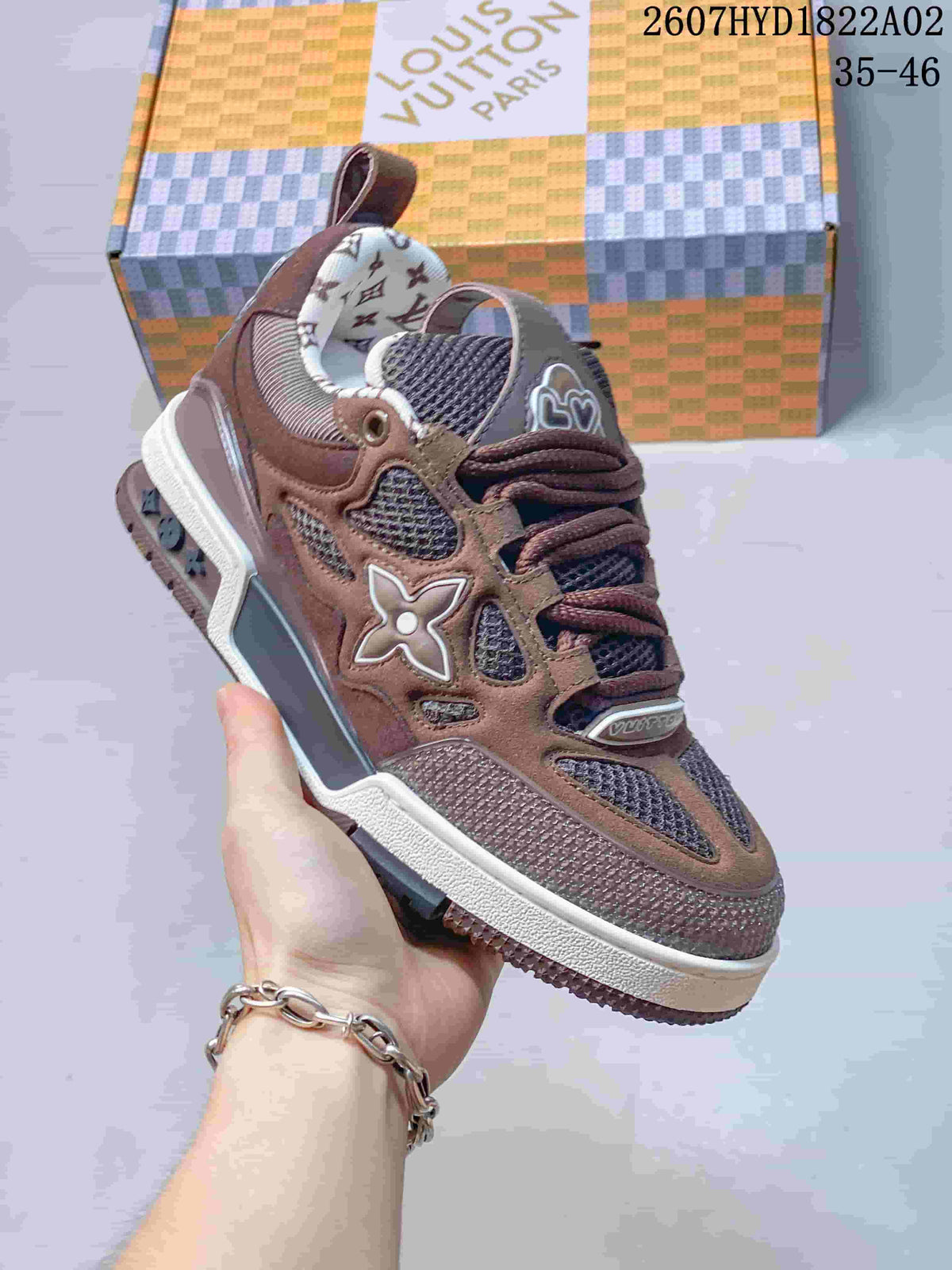 Close-up of a brown Trainer-style sneaker showing mesh panels, layered overlays, and a contrasting midsole.