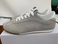 Side view of gray low-top Alo sneakers with white laces and a gum-colored outsole edge.