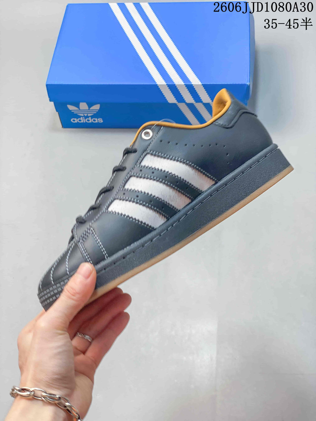 Side view of a charcoal adidas Superstar sneaker with three contrasting stripes