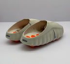 Rear three-quarter view showing the open backs, raised heel details, and orange outsole elements.