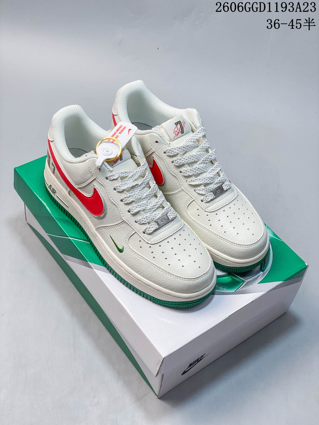 Pair of white Nike Air Force 1-style sneakers with red and green accents on a green-and-white box.