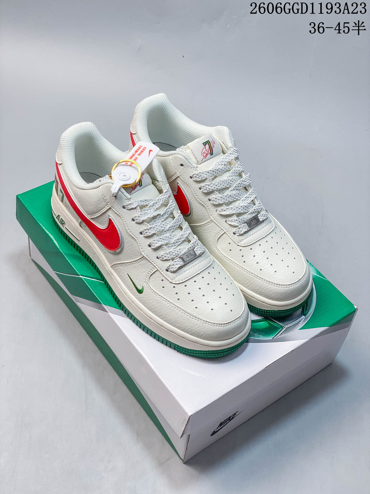 Pair of white Nike Air Force 1-style sneakers with red and green accents on a green-and-white box.