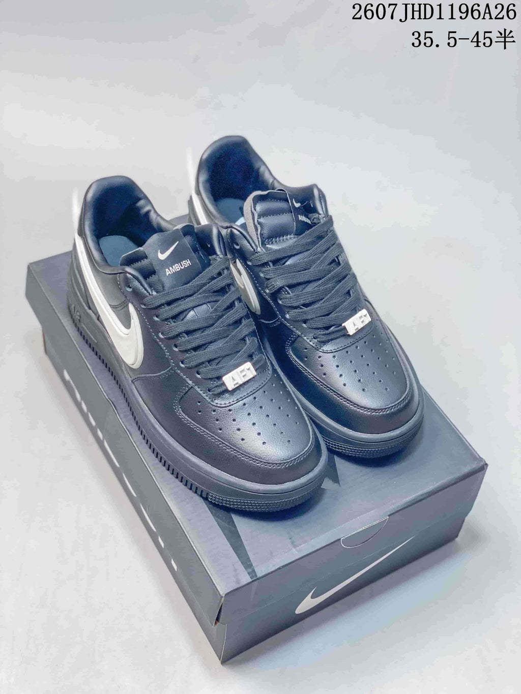 Black and white low-top sneakers displayed on a shoe box, with visible Nike and Ambush branding.