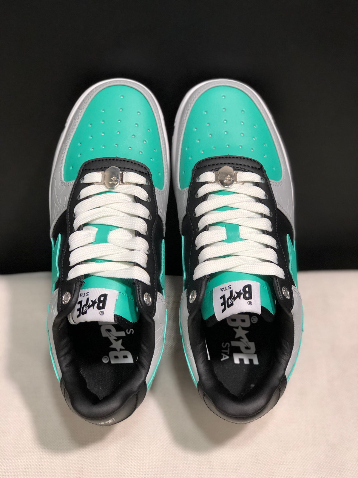 Top-down view showing turquoise perforated toe boxes, white laces and black lace panels.