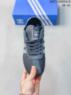 Top view of the dark gray lace-up sneaker showing the rounded toe, tongue label and white side stripes.