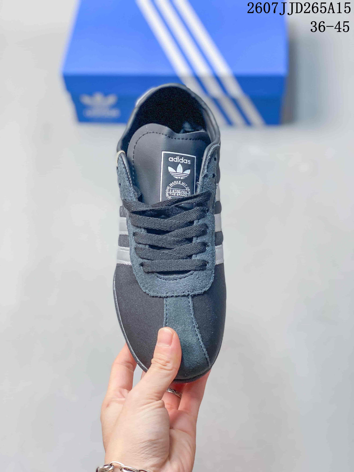 Top view of the dark gray lace-up sneaker showing the rounded toe, tongue label and white side stripes.