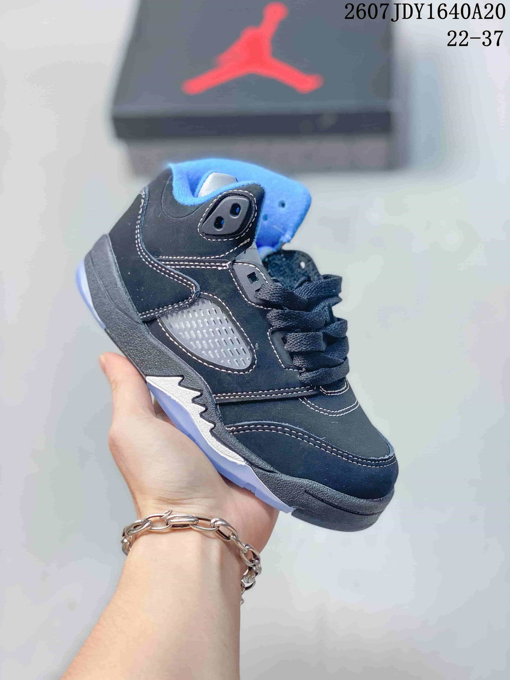 Black and gray kids' mid-top sneaker with blue collar lining and a translucent-looking outsole.