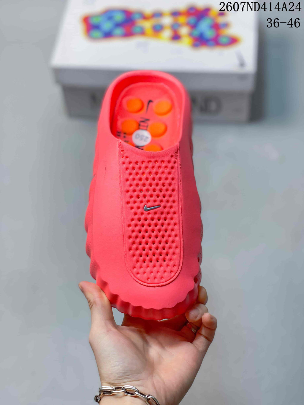 Top view of the coral-red slip-on mule showing the perforated upper panel, Nike Swoosh, and orange insole details.