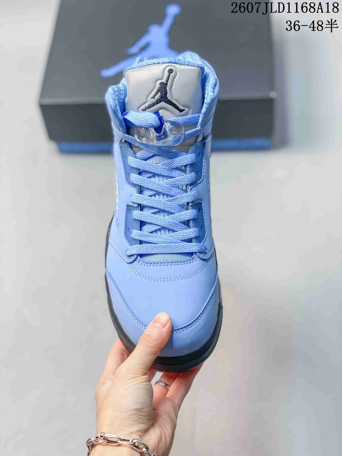 Front view of one light blue high-top sneaker showing the padded tongue, Jordan branding, laces and rounded toe.