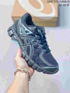 Angled side view of a black and gray ASICS Gel-Kayano 20 sneaker showing the side logo, mesh-look panels, layered overlays, and segmented outsole; image text shows style code 2607JYD1549A19 and size range 39–47.5.